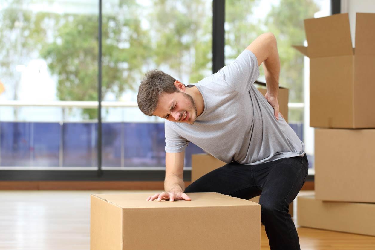 man hurting back while lifting boxes at work