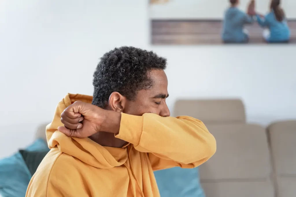 worker with chemical pneimonitis coughing into elbow