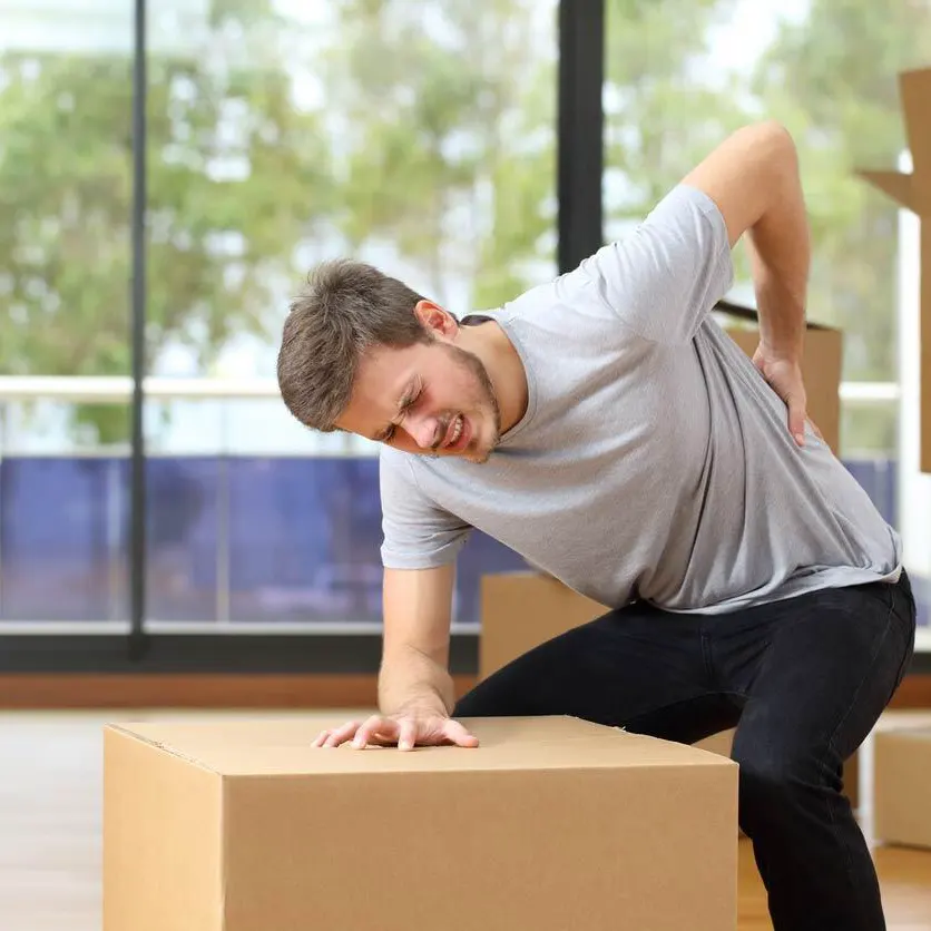 Worker experiencing lower back pain after lifting a heavy box, representing a potential work-related disc injury claim in Missouri.