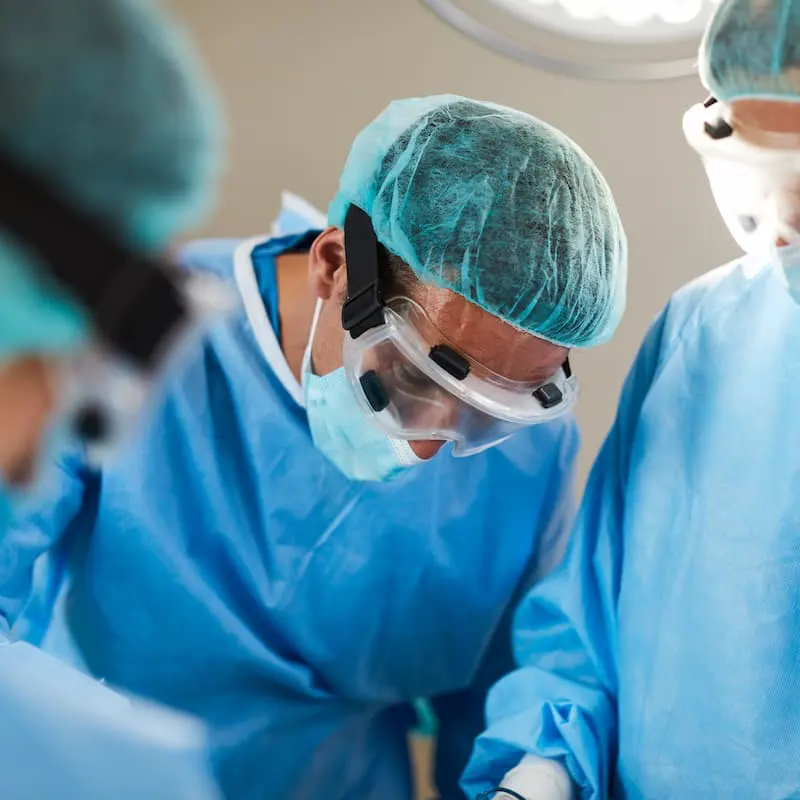 Surgeons performing surgery in hospital operating room — workers' comp medical procedure concept.