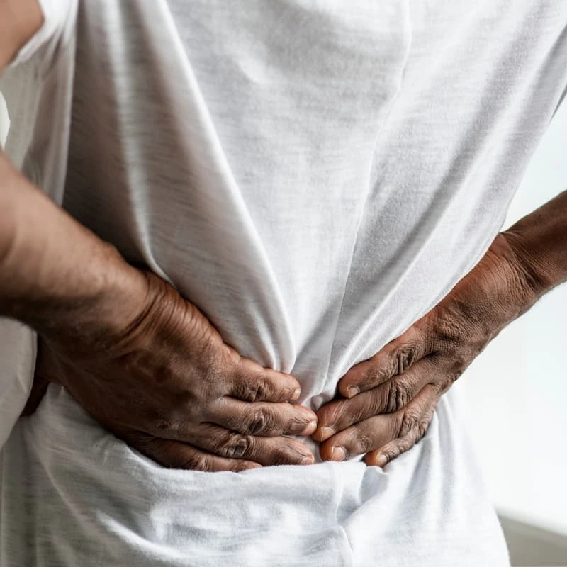 Person holding lower back in pain, illustrating a work-related back injury claim in Missouri.