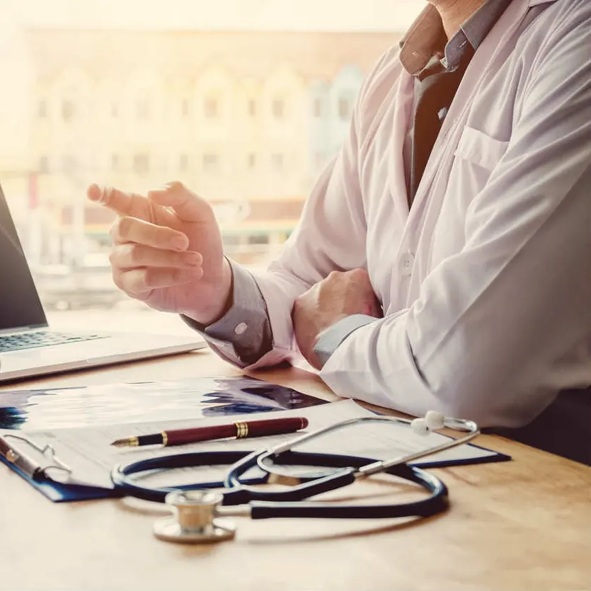 Doctor reviewing medical records at desk with stethoscope and X-rays, discussing second opinion for a Missouri workers’ compensation case