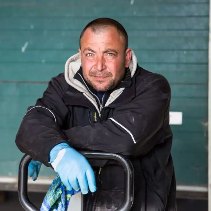 Injured Missouri warehouse worker in protective gloves leaning on equipment, illustrating workers’ comp claim denied due to ‘not at greater risk than public’.