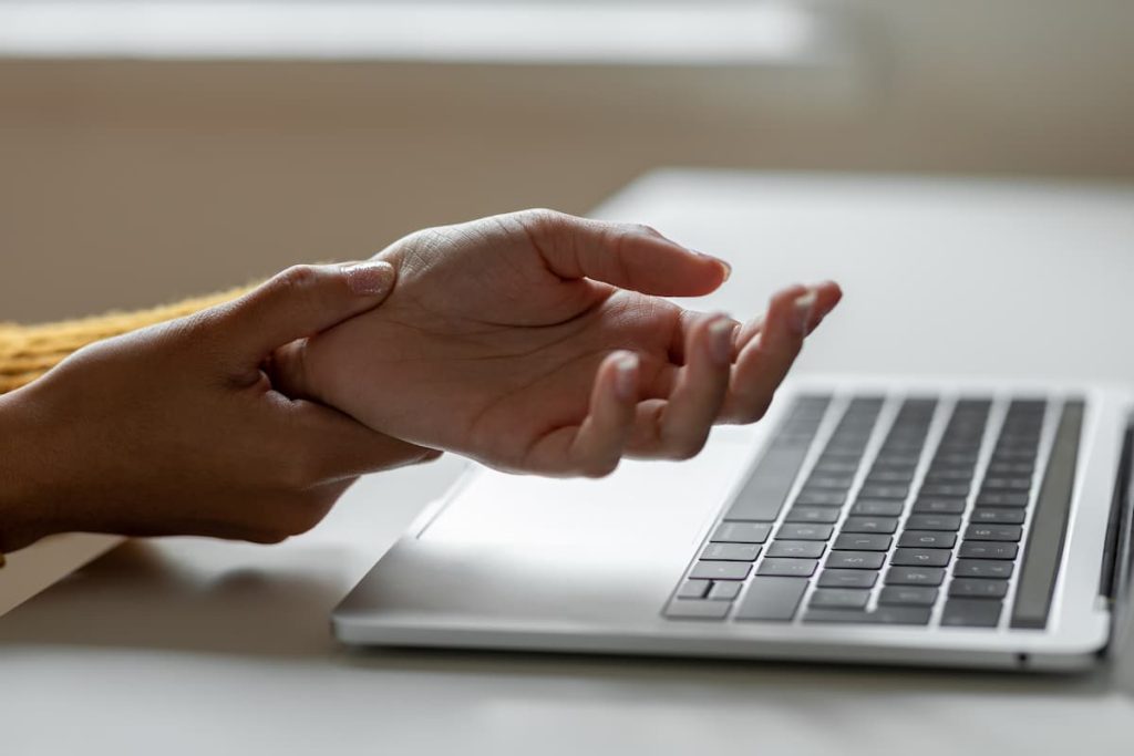 a woman holds her wrist after an injury from typing